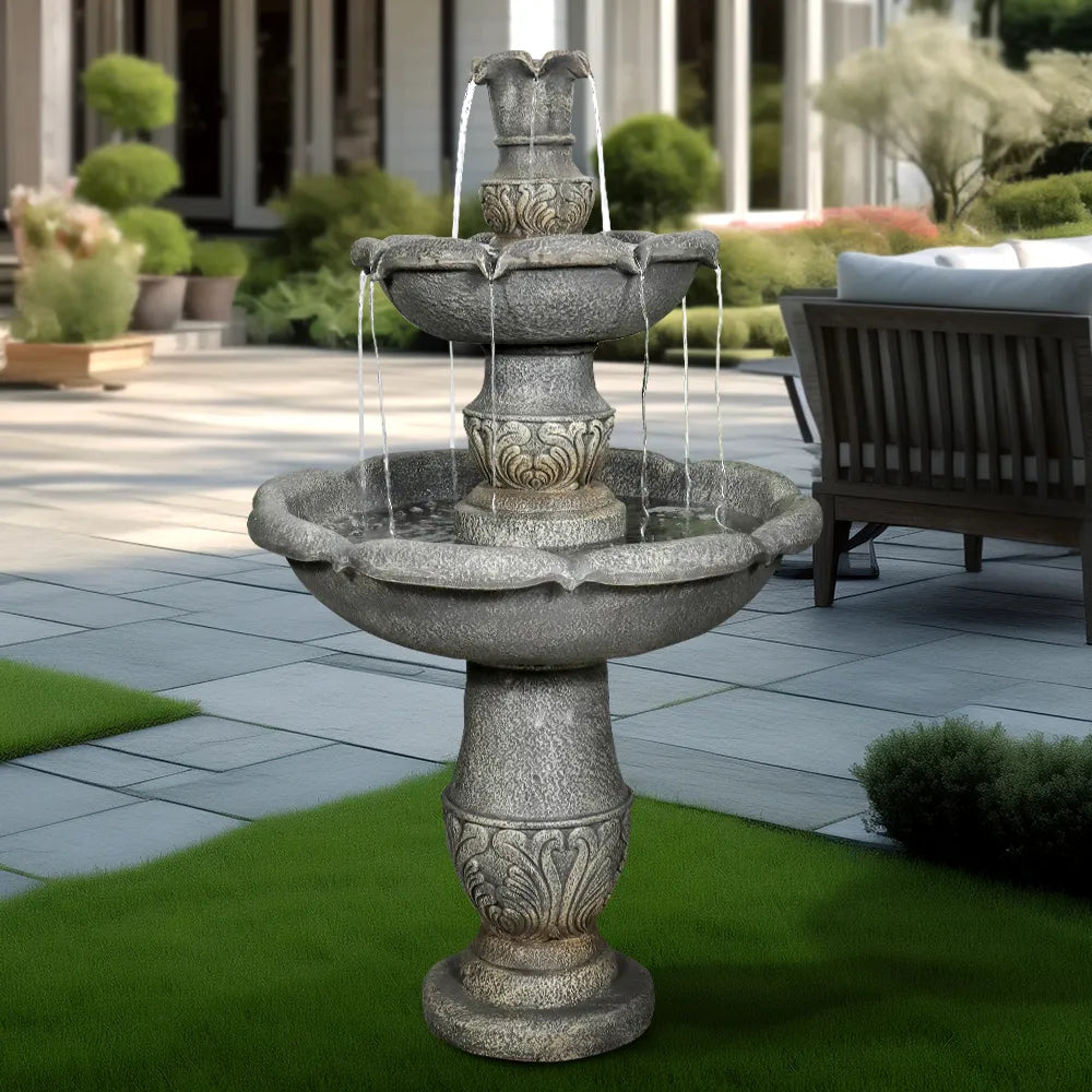 2-tier classical outdoor fountain with cascading water streams on a paved garden patio.