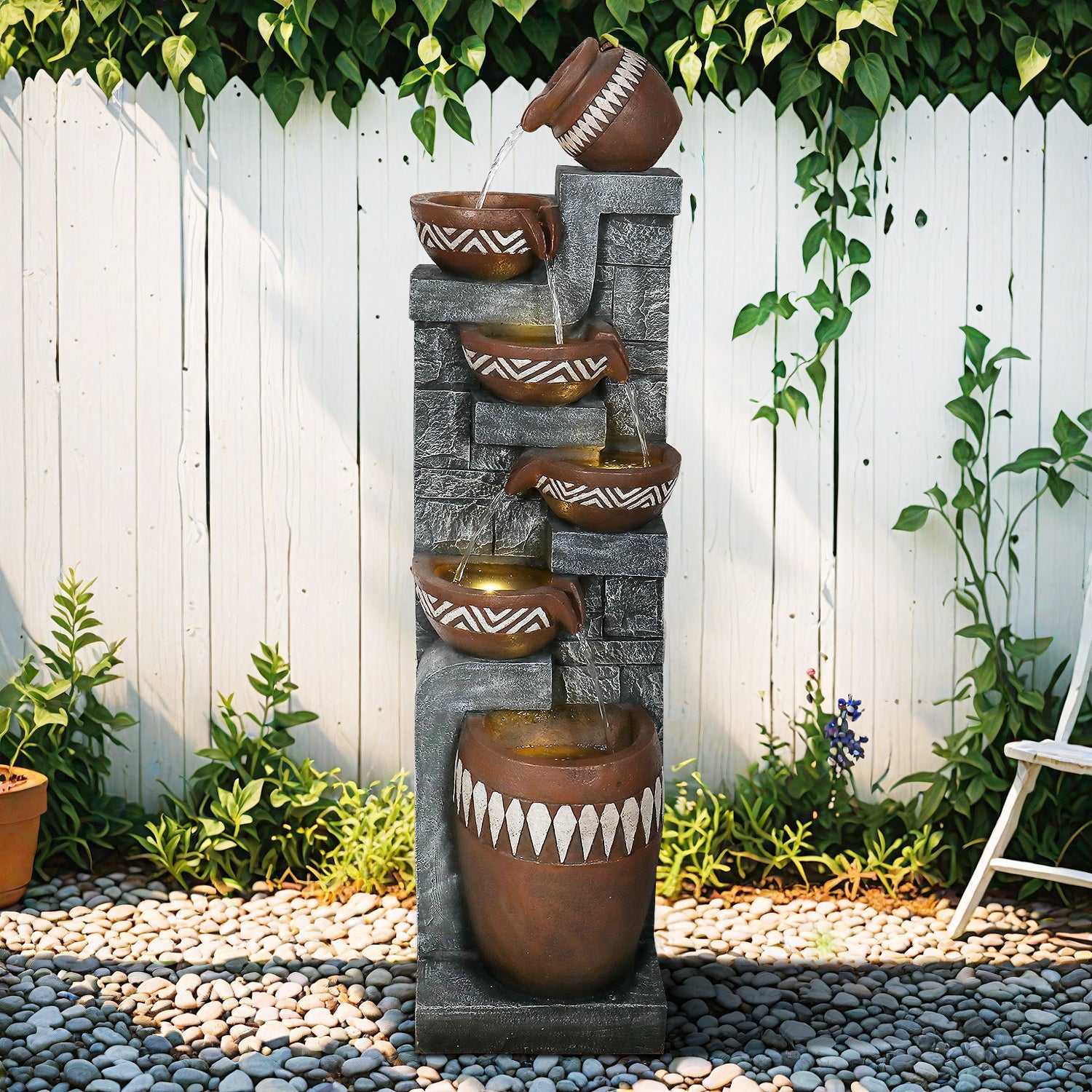 56.6" 6-tiered patterned jar waterfall fountain stands in a detailed bohemian backyard on a meticulous river pebble patio, water cascading vibrantly in natural sunlight.