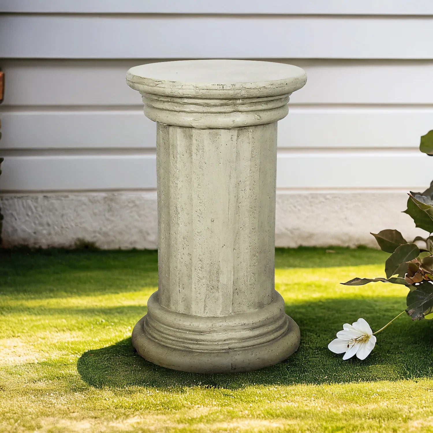 Classic 20-inch pedestal side table in faux stone finish on a lush green outdoor lawn.