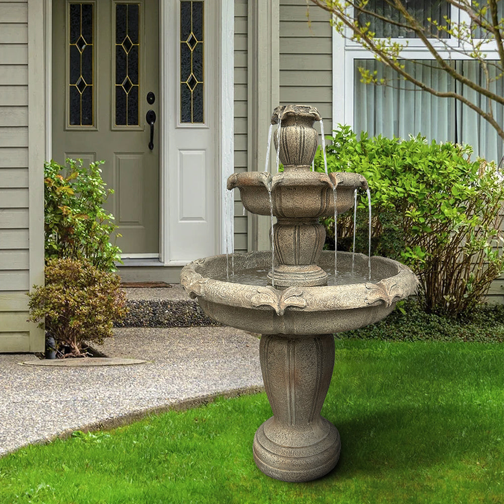 Concrete 3 tier water fountain with fleur de lis relief running in a garden