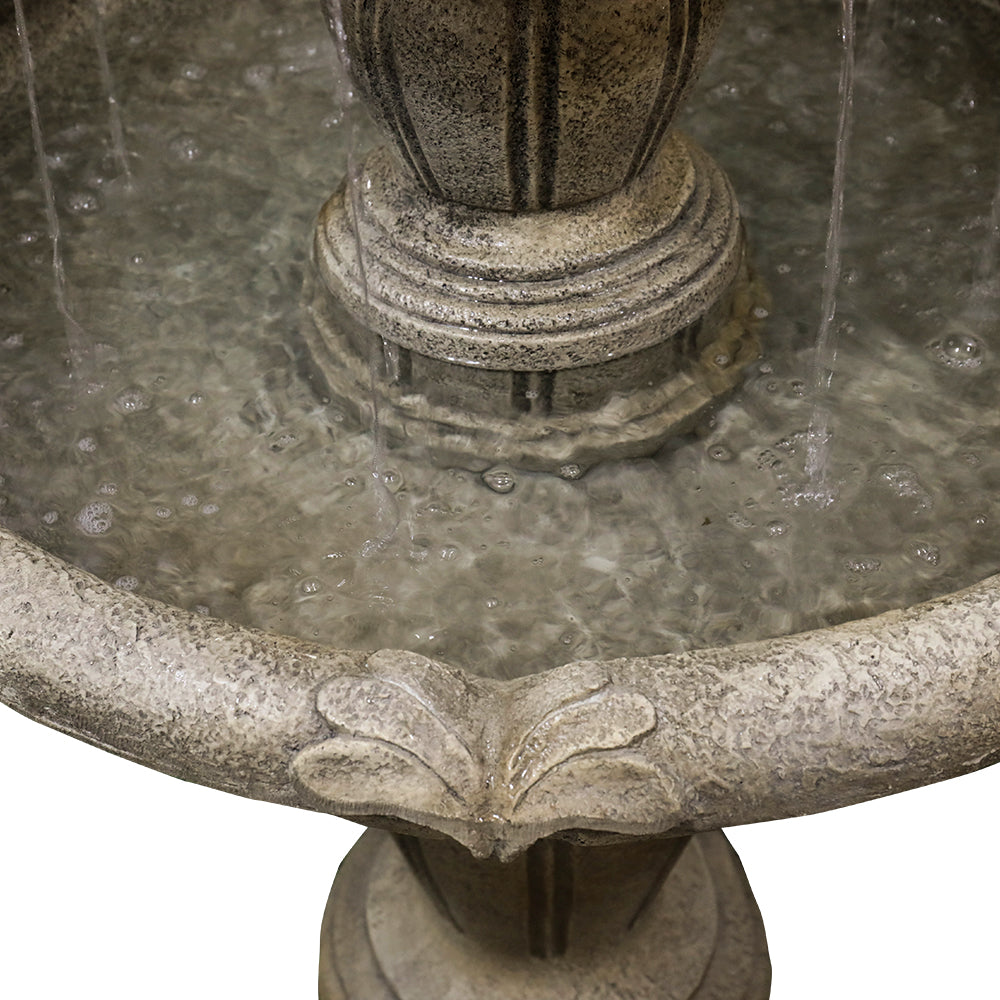 Detailed view of water elegantly cascading from the middle tier of the stone-look fountain.