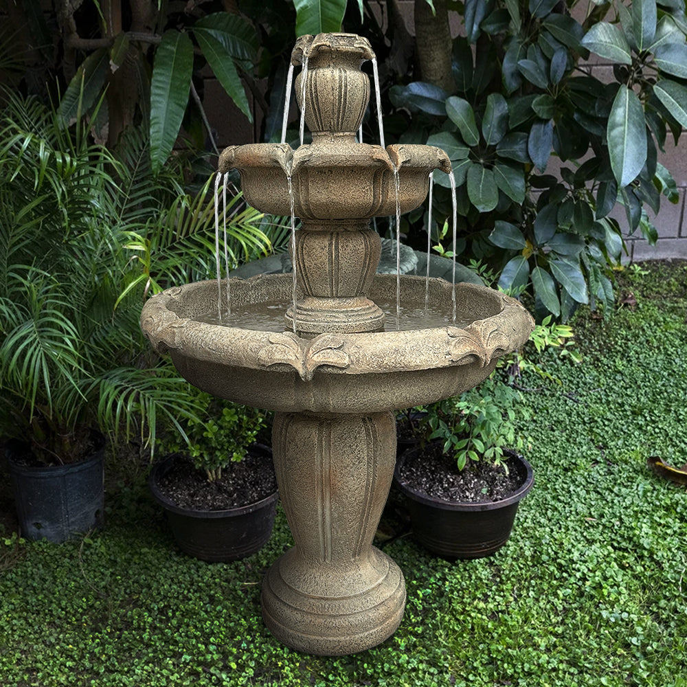 Large 3-tier concrete floor fountain creating a peaceful retreat among lush garden plants.