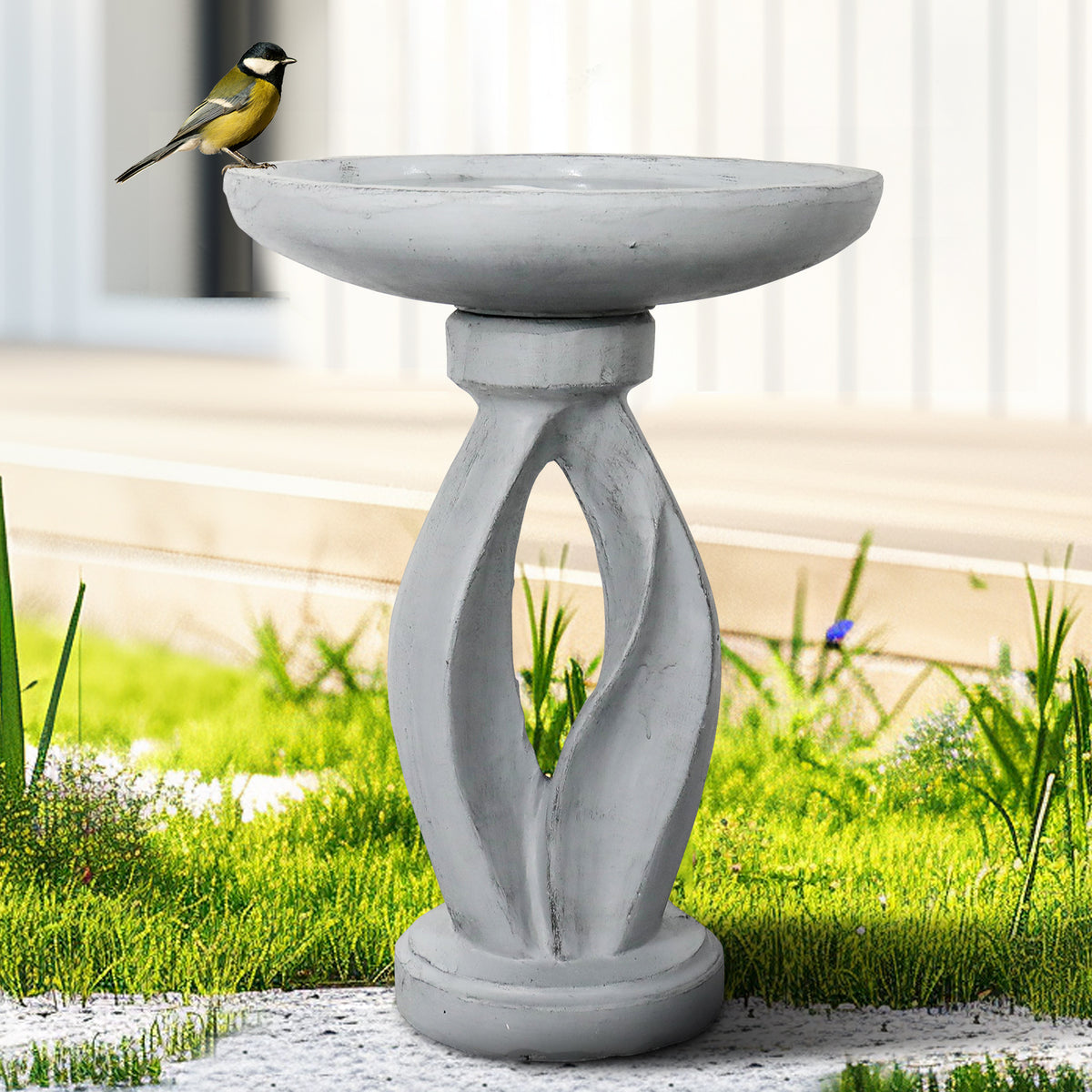 Modern concrete yard statue bird bath serving as a contemporary focal point on a green lawn.