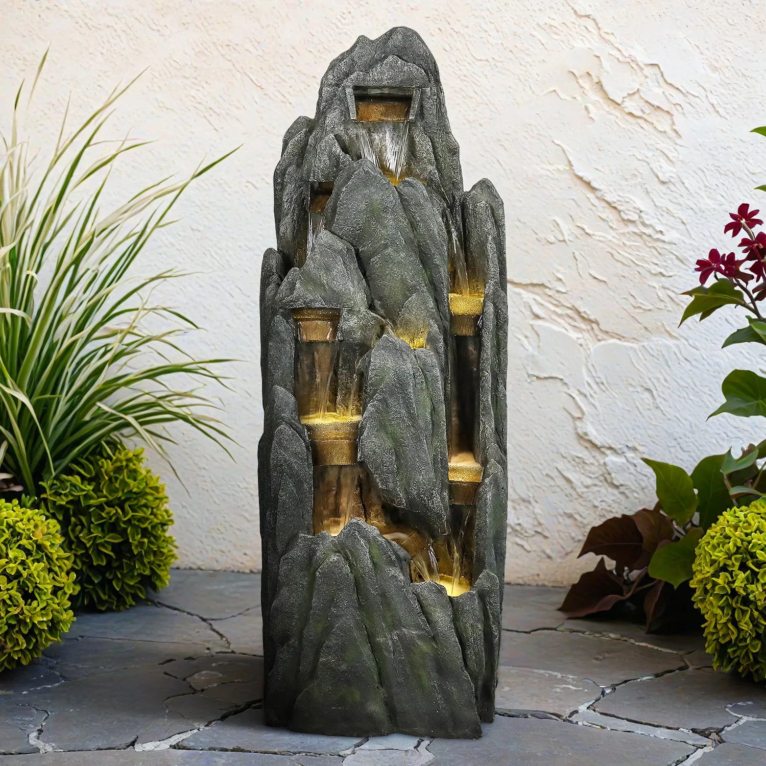 Naturalstonestylecascadingrockfountainplacedagainstalight-coloredpatiowall