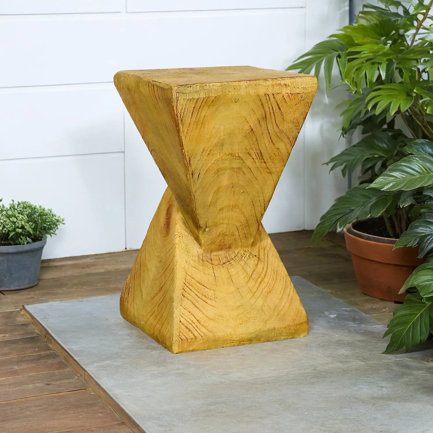 Sculptural golden pyramid end table for garden or porch decor on a sleek tiled floor.