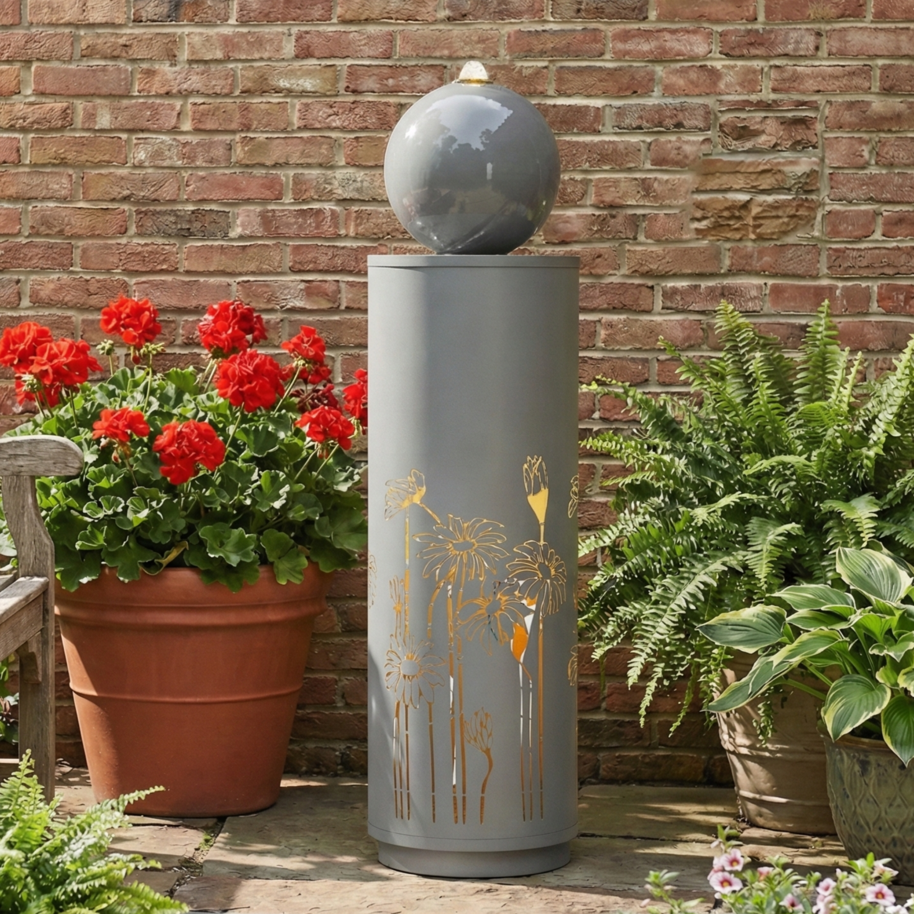gilded vine cutout sphere fountain beside red geranium flowers