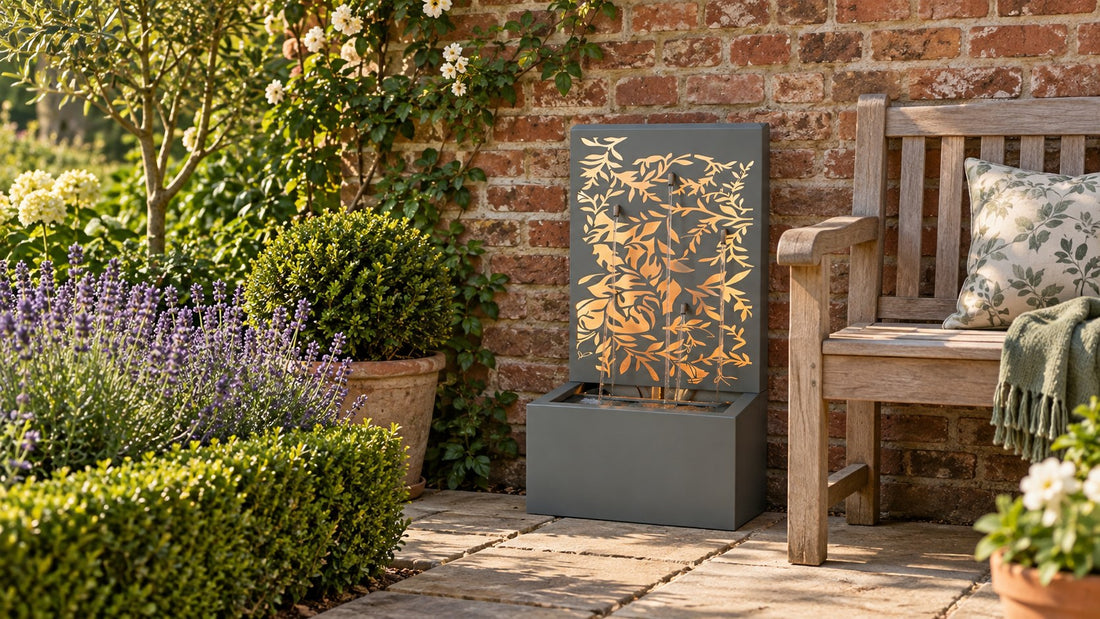 Metal wall fountain with a glowing cut leaf panel standing against a brick wall beside a wooden garden bench