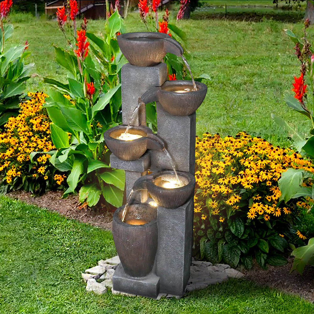 Cascading jar water feature standing elegantly on a fresh green lawn in the sun