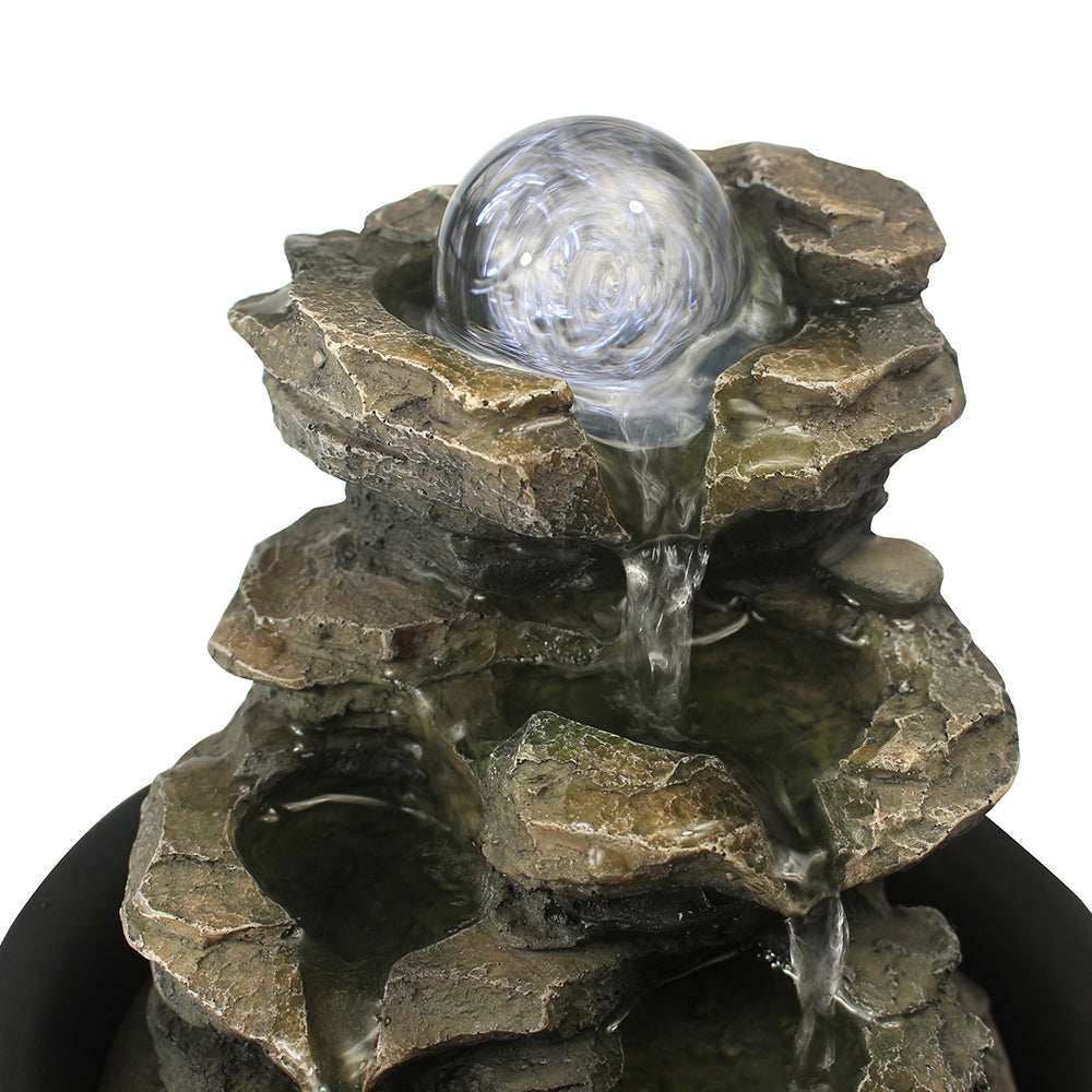 Close-up of the crystal-like orb spinning in the water flow, illuminated by colored LEDs
