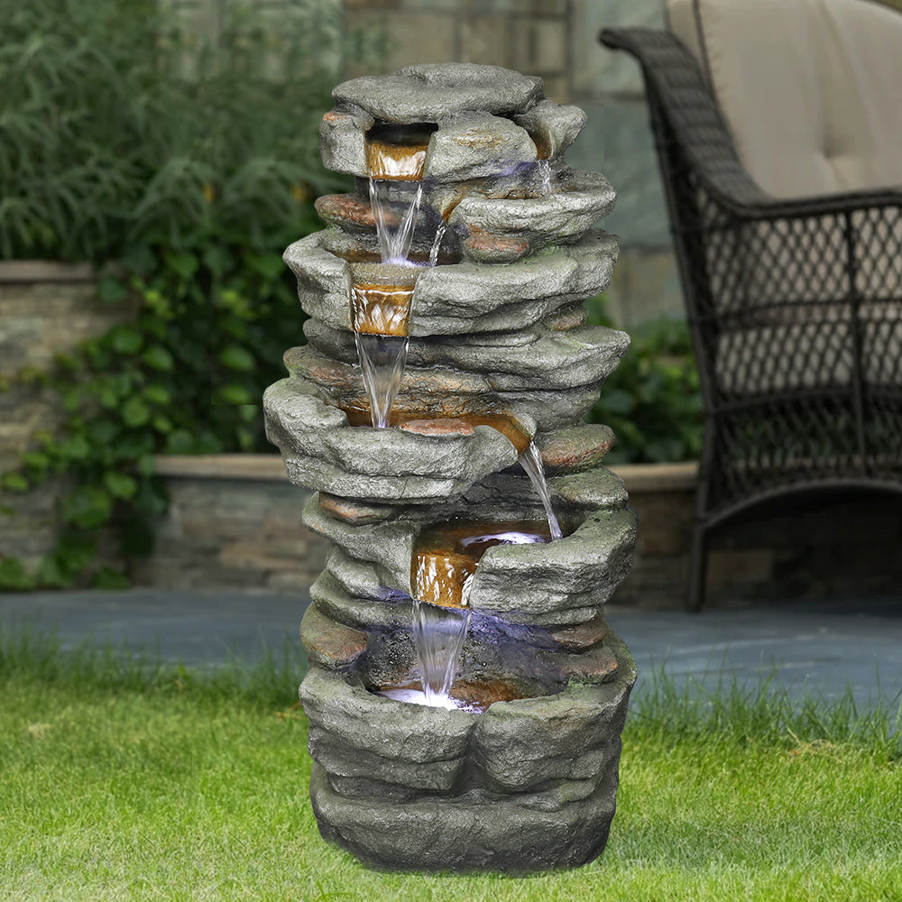 Realistic gray stone and moss outdoor waterfall standing beautifully on a lush green grass lawn.