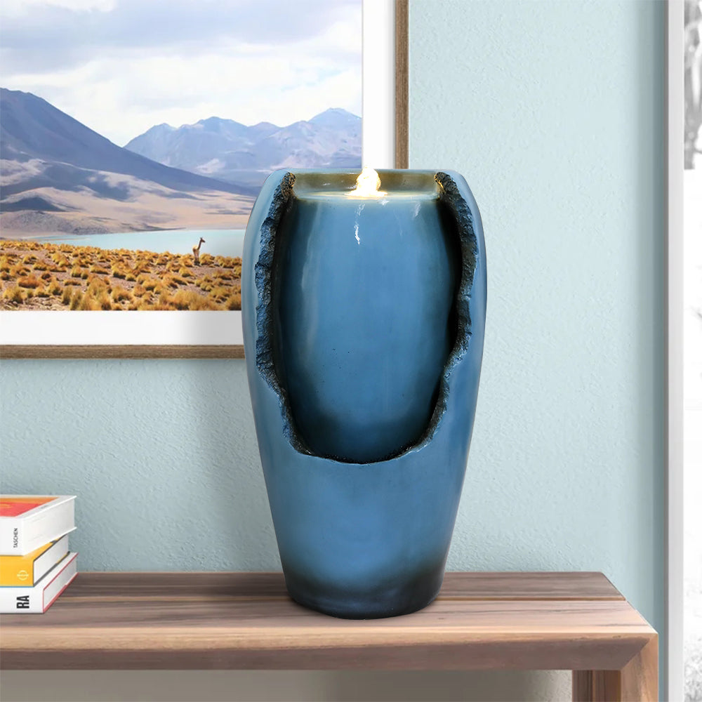 Blue vase resin tabletop water fountain with lights on a wood console table