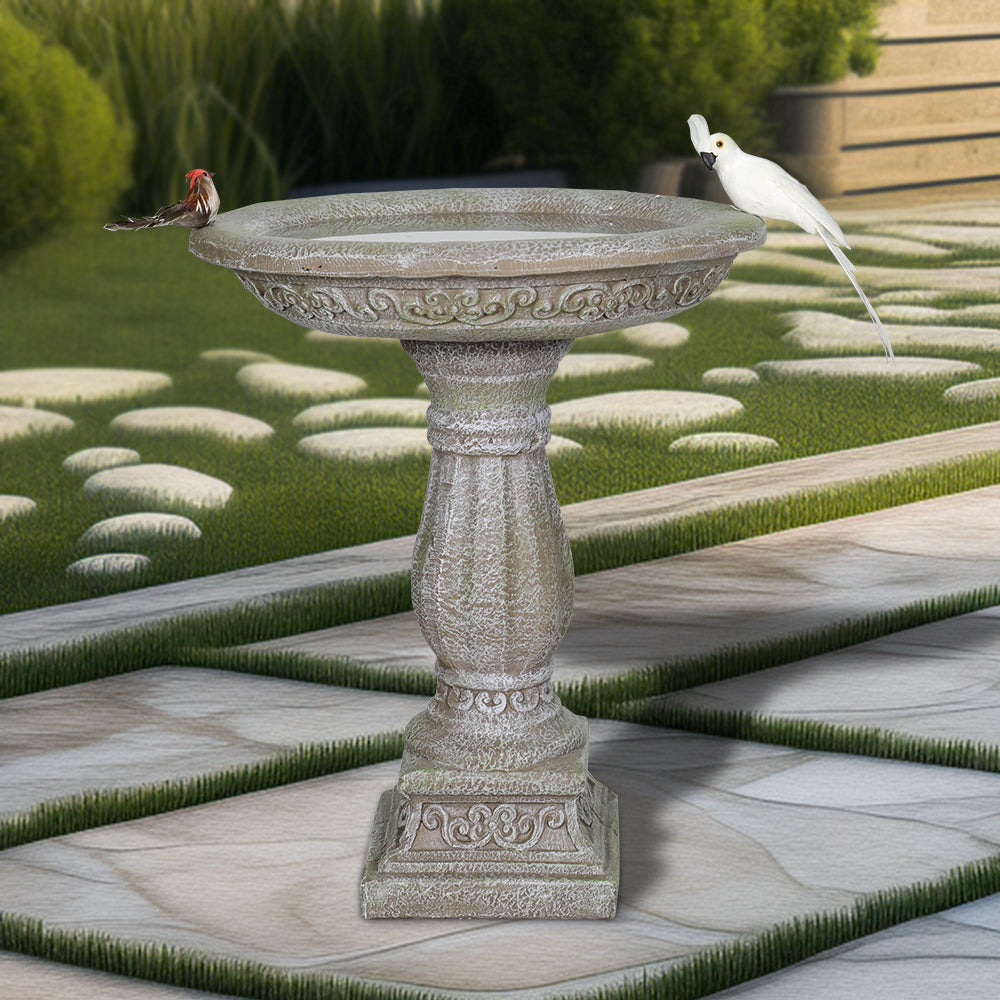 23" tall antique pedestal concrete birdbath in a lush traditional garden
