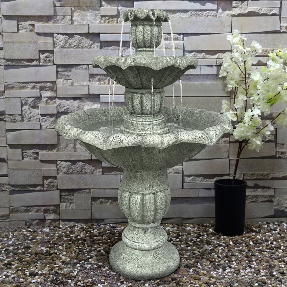 39.3"H concrete lotus fountain positioned against a textured backyard wall