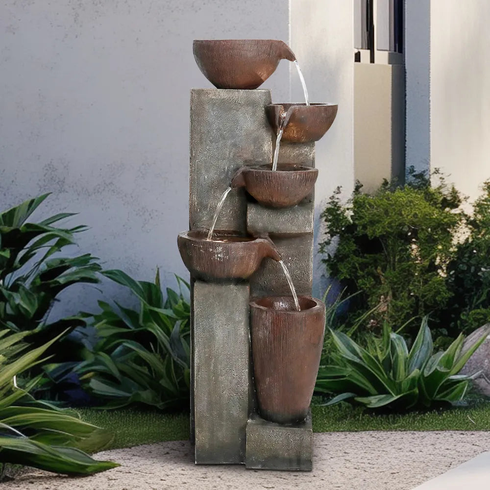 5-tier cascading water fountain with copper-look bowls and stone base in a modern outdoor patio setting.