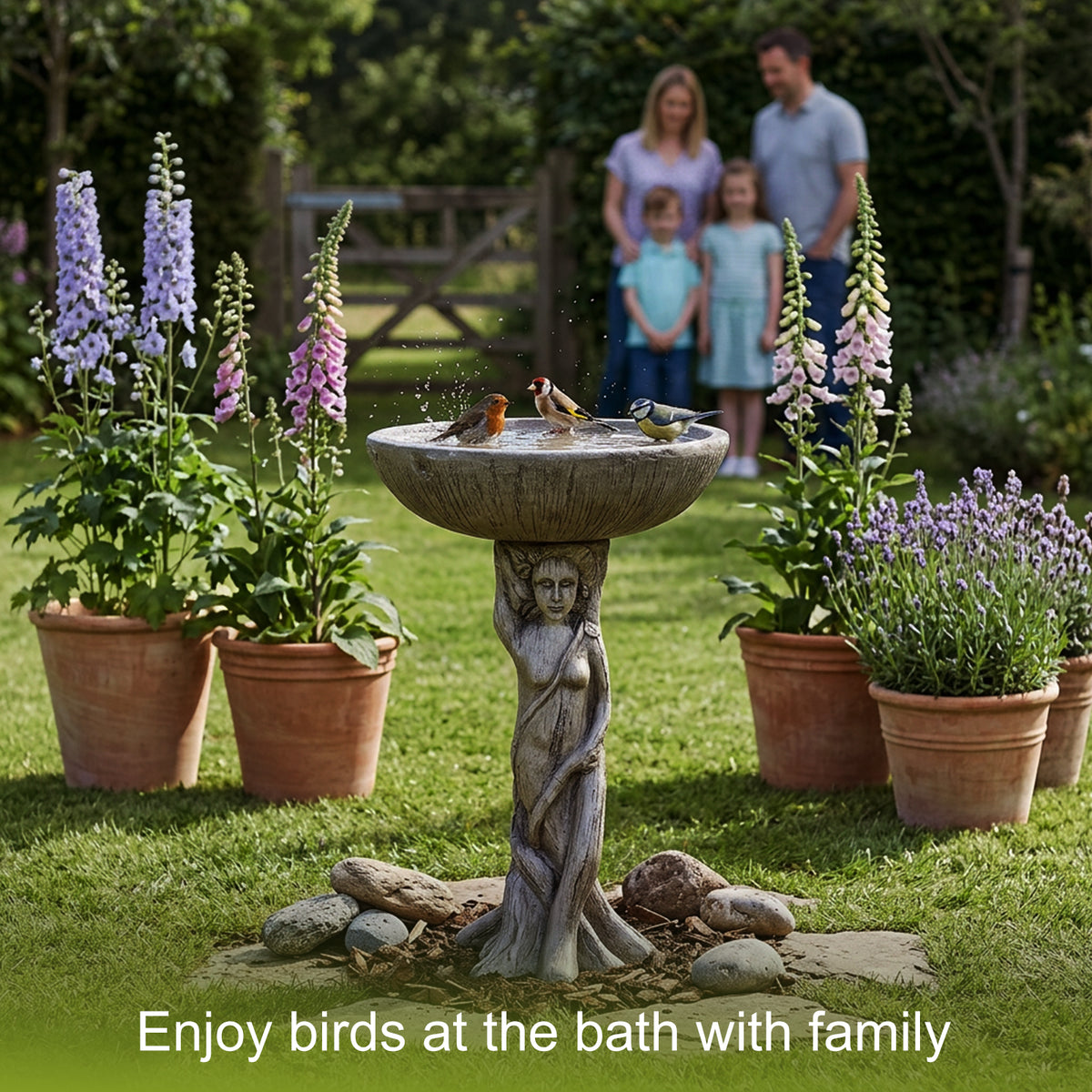 A family enjoying their backyard garden with the elegant goddess bird bath in the foreground.