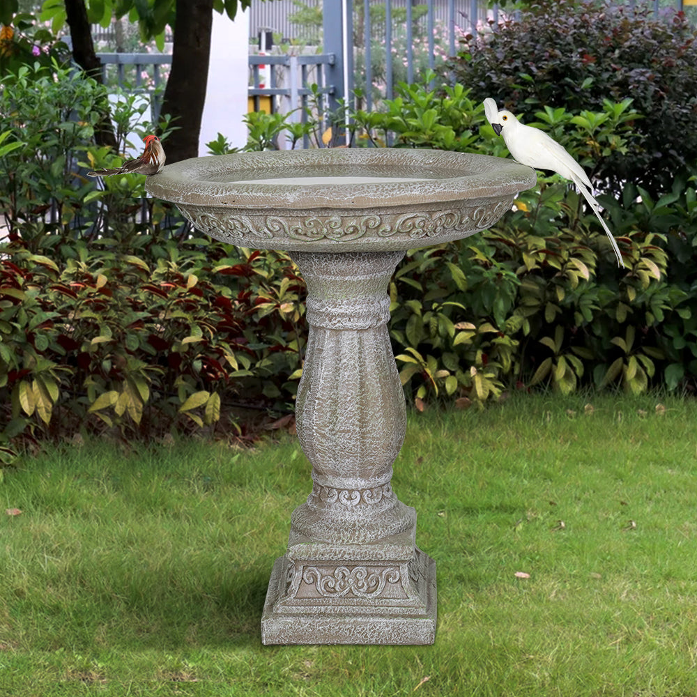 Antique stone-like concrete birdbath in a backyard