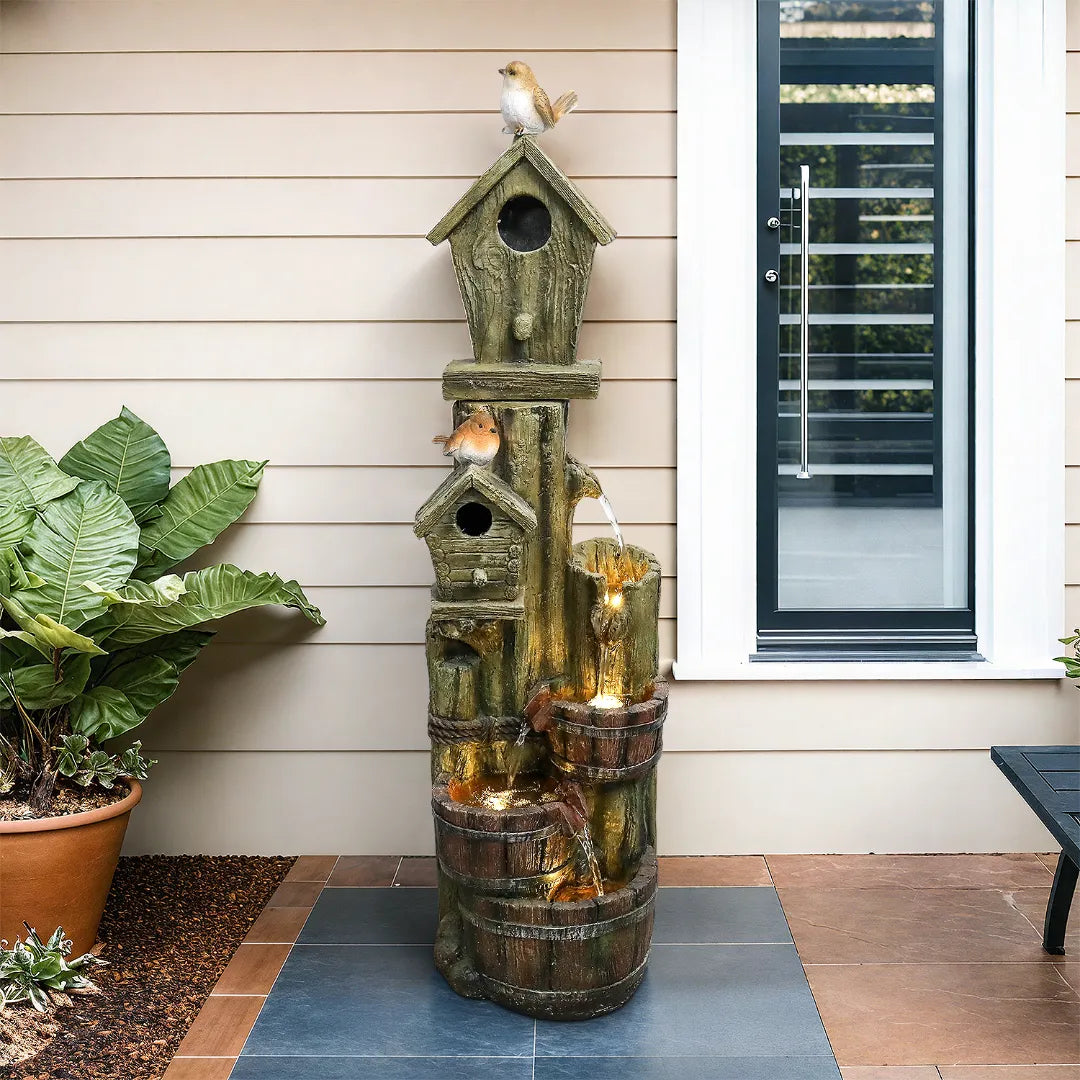Cascading_birdhouse_waterfall_fountain_with_warm_LED_lights_placed_on_a_modern_patio_deck.
