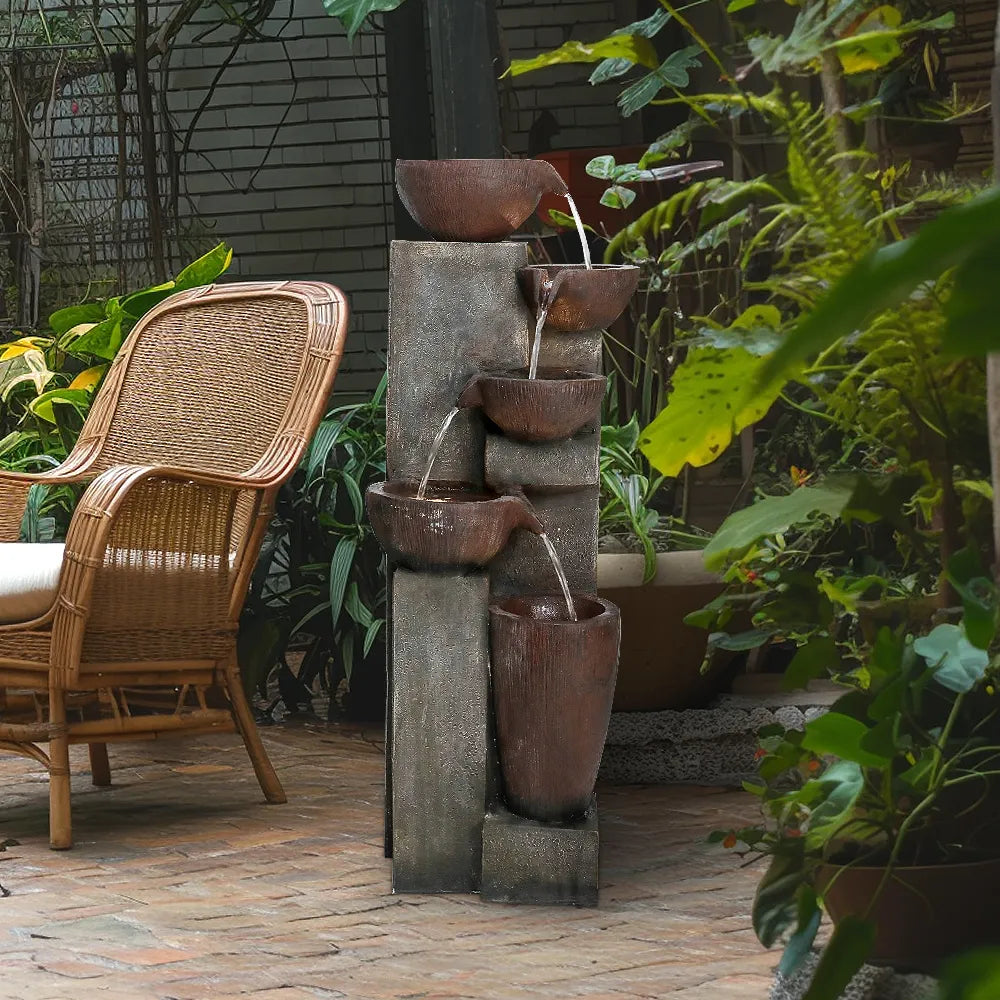 Cascading garden fountain placed near rattan outdoor furniture, highlighting its use as a relaxing water feature.
