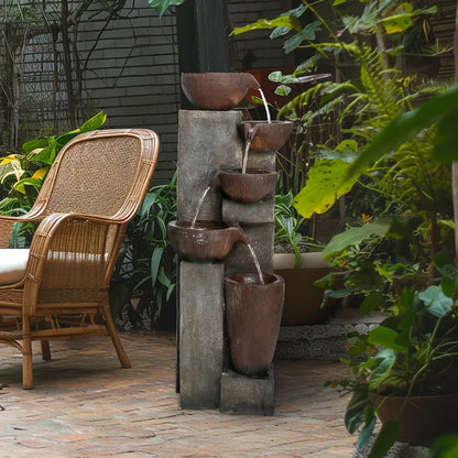 Cascading garden fountain placed near rattan outdoor furniture, highlighting its use as a relaxing water feature.