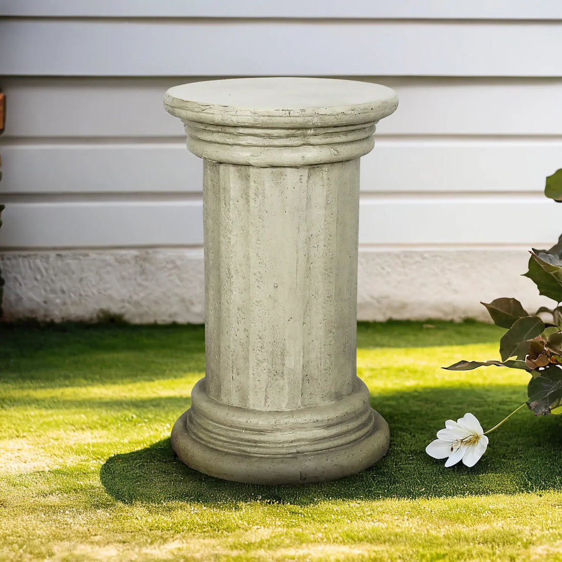 Classic 20-inch pedestal side table in faux stone finish on a lush green outdoor lawn.