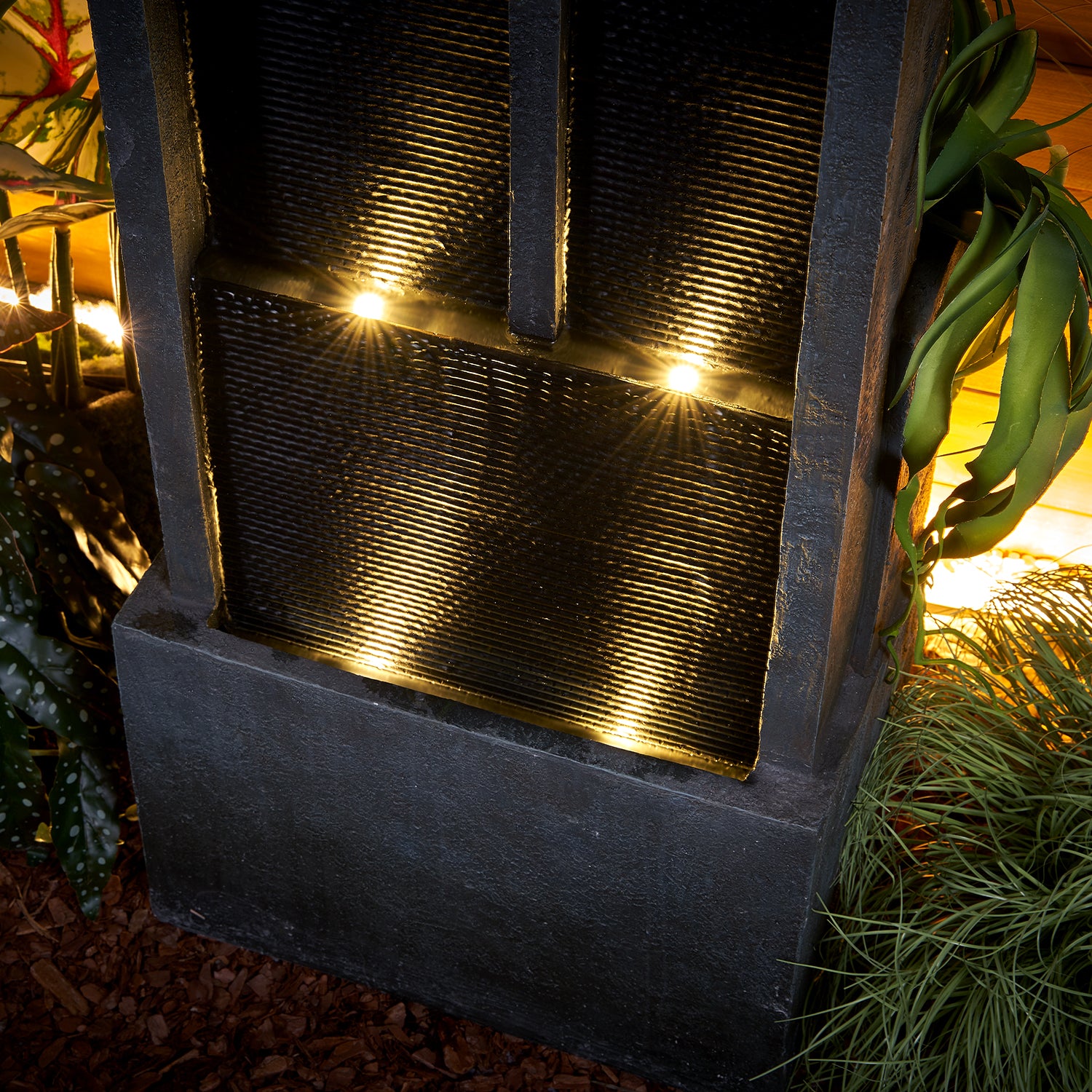 Close-up of the soothing water trickling into the lower basins illuminated by warm LED lights.