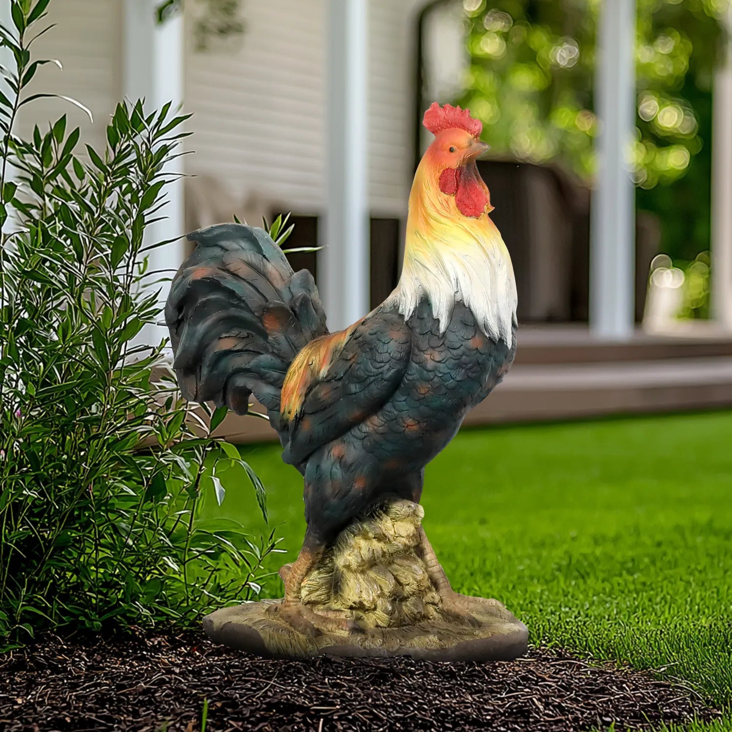 Colorful 22.4-inch rooster garden statue standing in a garden bed with green plants.