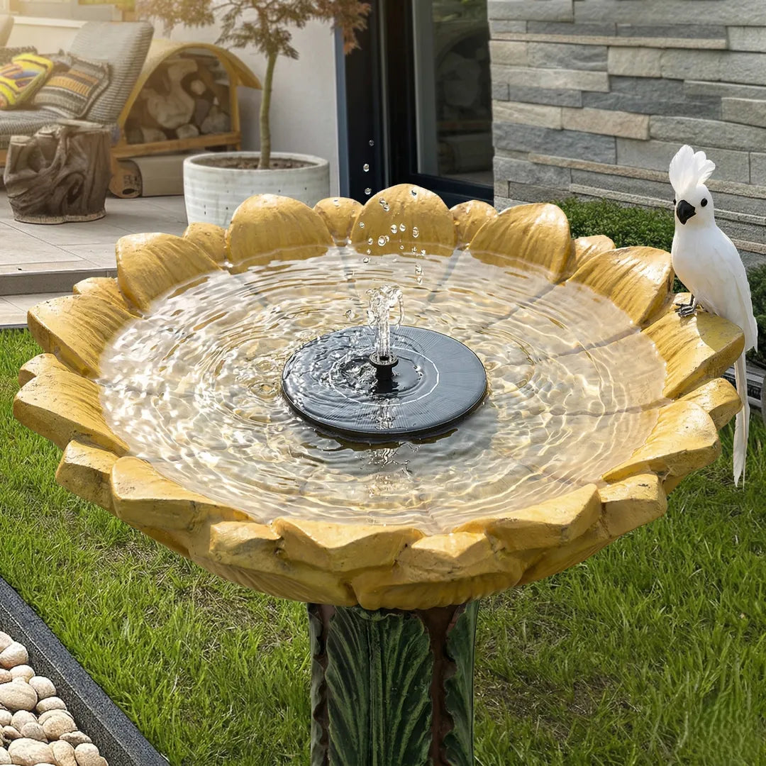Concrete bird bath with solar fountain pump creating gentle water movement in a backyard garden