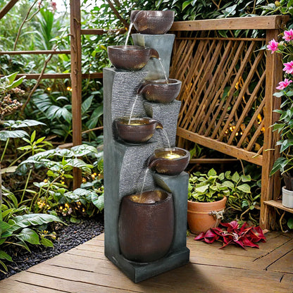 Contemporary floor-standing water feature with cascading bowls and moss accents in a garden setting.