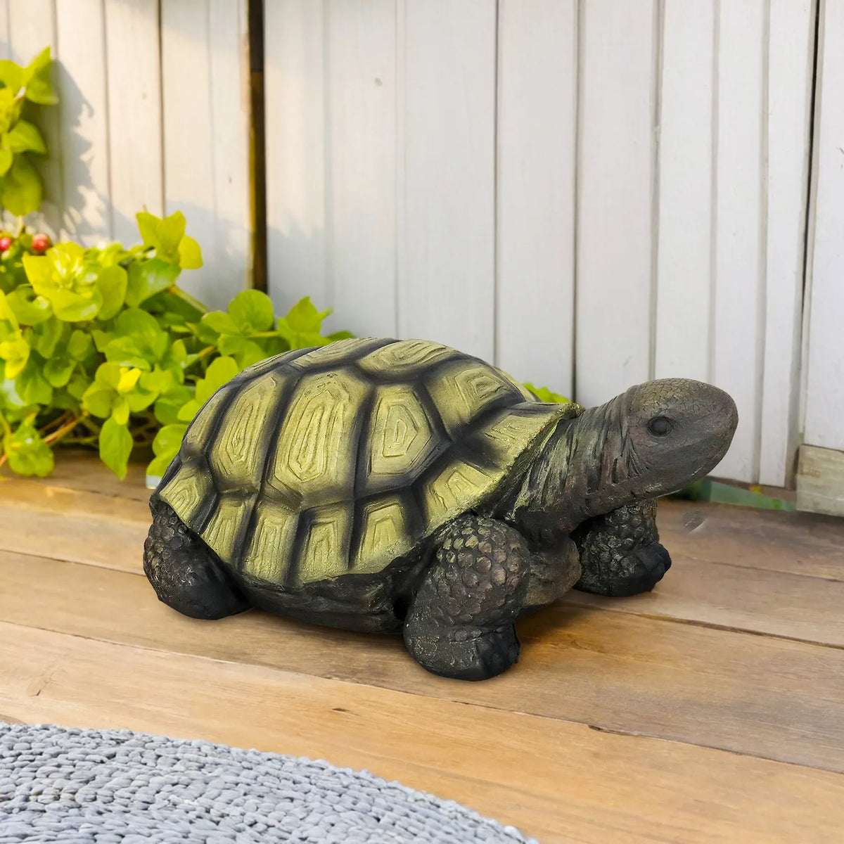 Durable concrete turtle statue on a wooden outdoor deck.