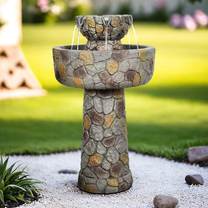 Faux stone concrete bird bath placed as a centerpiece in a modern landscaped garden with white pebbles.