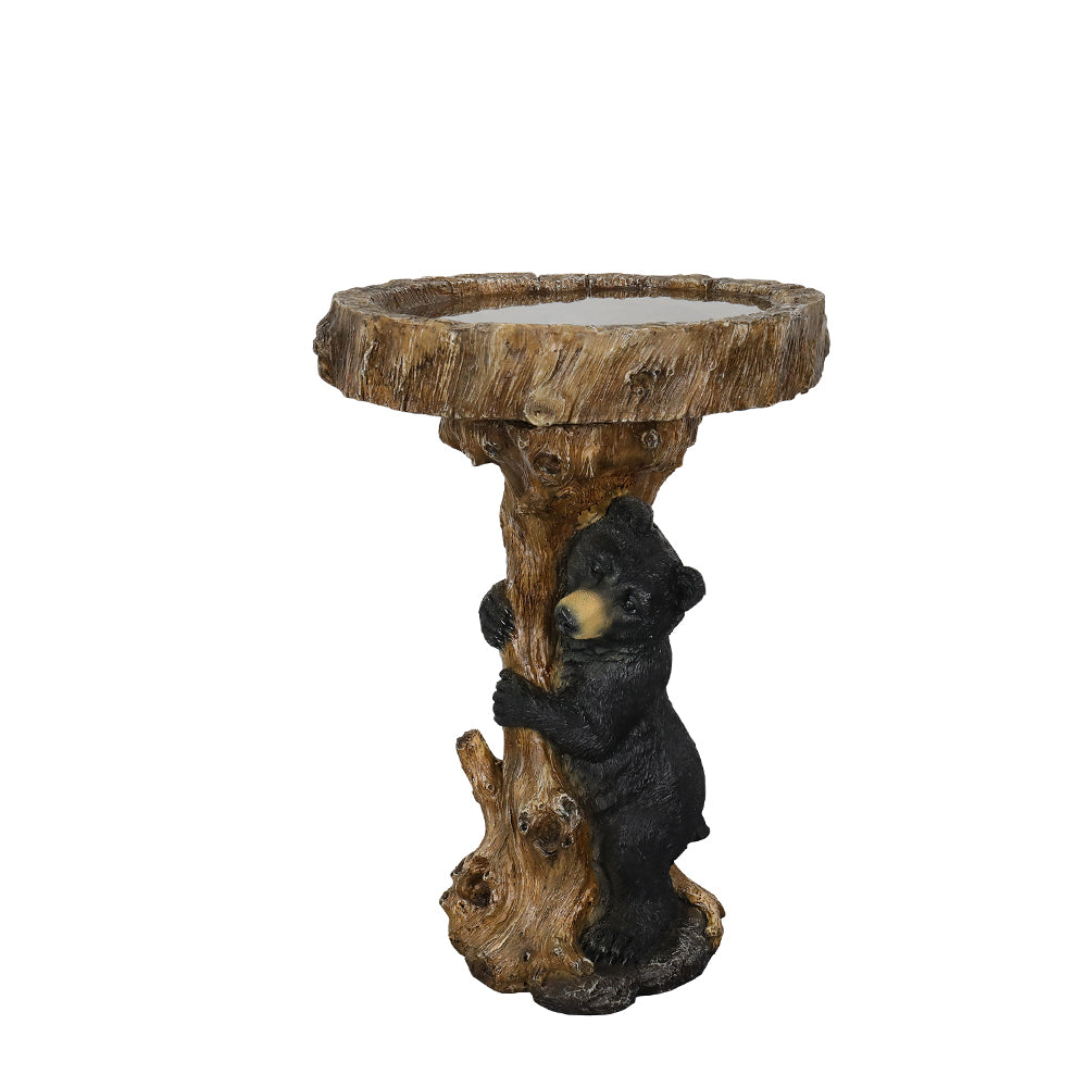 Full view of the black bear hugging a tree stump bird bath on a white background.