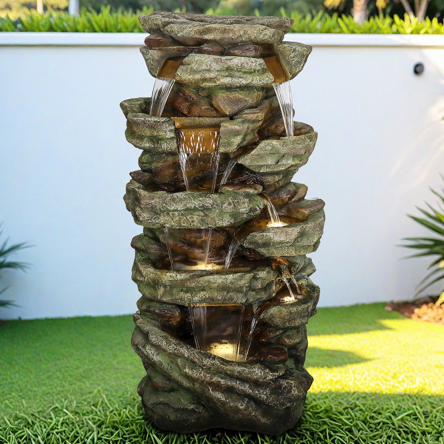 Large 47.2"H cascading rock outdoor waterfall fountain integrated into a green garden lawn.