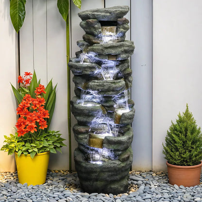 Layered rock water feature positioned naturally next to a rustic outdoor garden fence