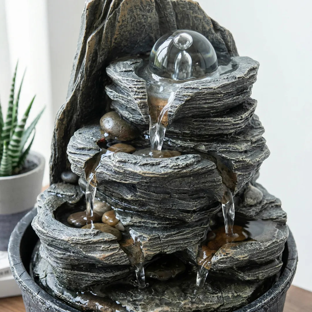 Macro close-up of water flowing smoothly down a slate-look tabletop fountain with zero splashing.