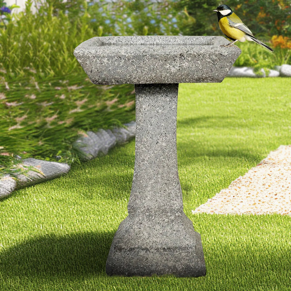 Modern concrete birdbath on a fresh green lawn