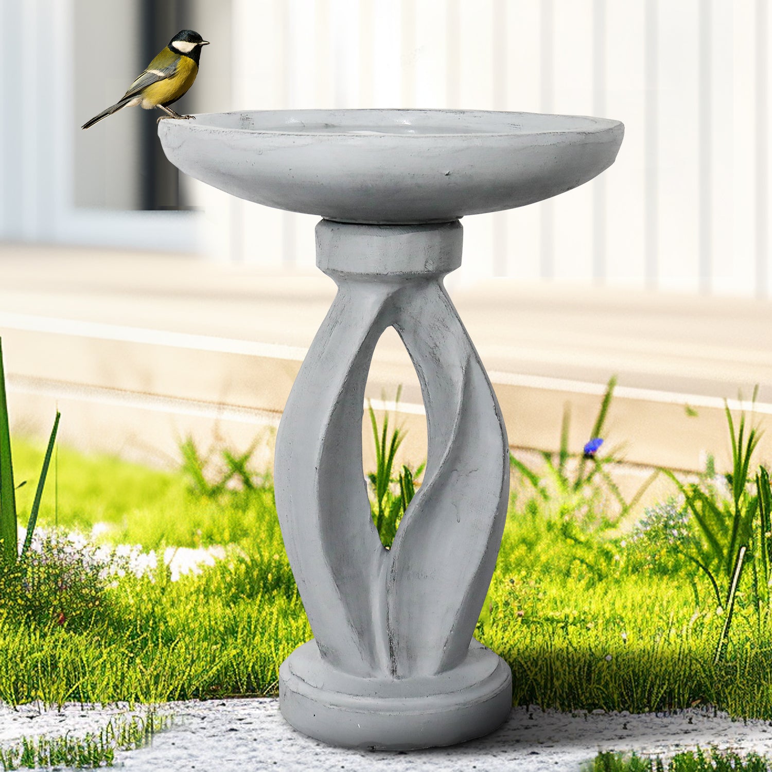 Modern concrete yard statue bird bath serving as a contemporary focal point on a green lawn.