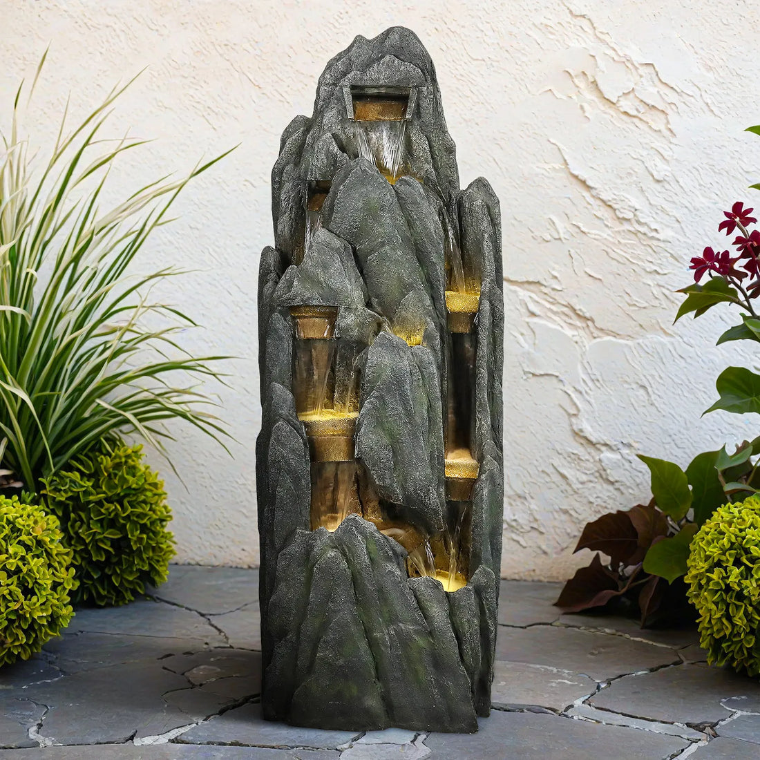 Naturalstonestylecascadingrockfountainplacedagainstalight-coloredpatiowall