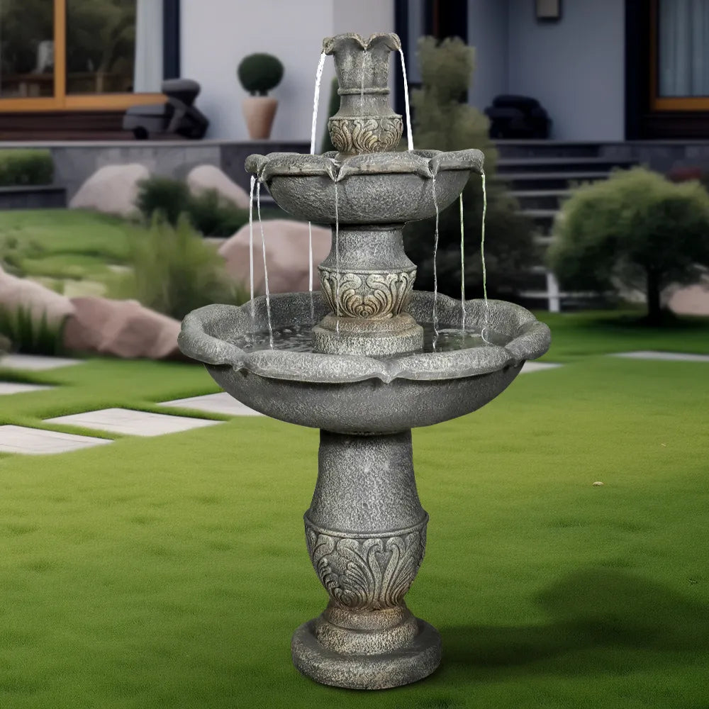Rustic outdoor concrete waterfall fountain on a green lawn
