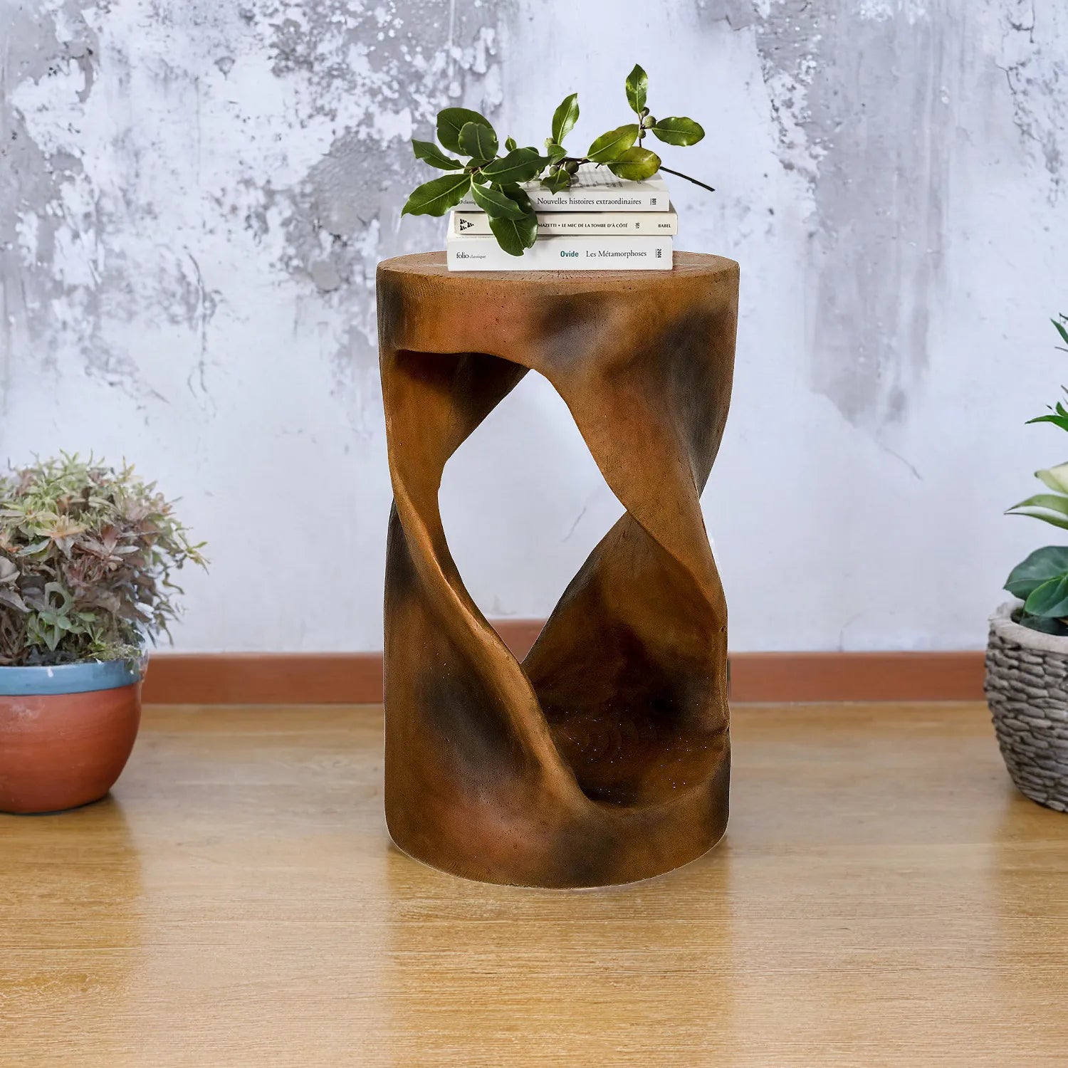 Sculptural concrete end table in a minimalist indoor setting with a grey wall background.