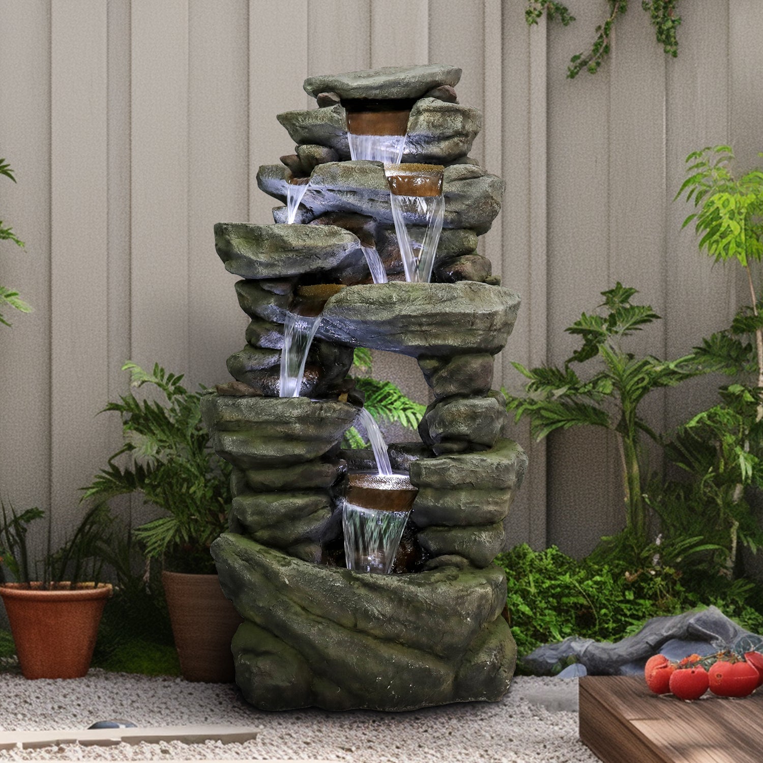 Sturdy 46.5kg poly-resin rock outdoor fountain placed elegantly against a backyard fence.