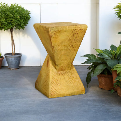 Stylish yellow concrete side table placed on a modern outdoor patio next to green plants.
