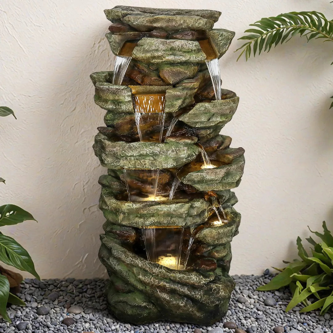 Tall natural stone-look fountain next to a rustic garden fence