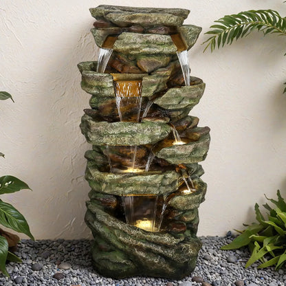 Tall natural stone-look fountain next to a rustic garden fence