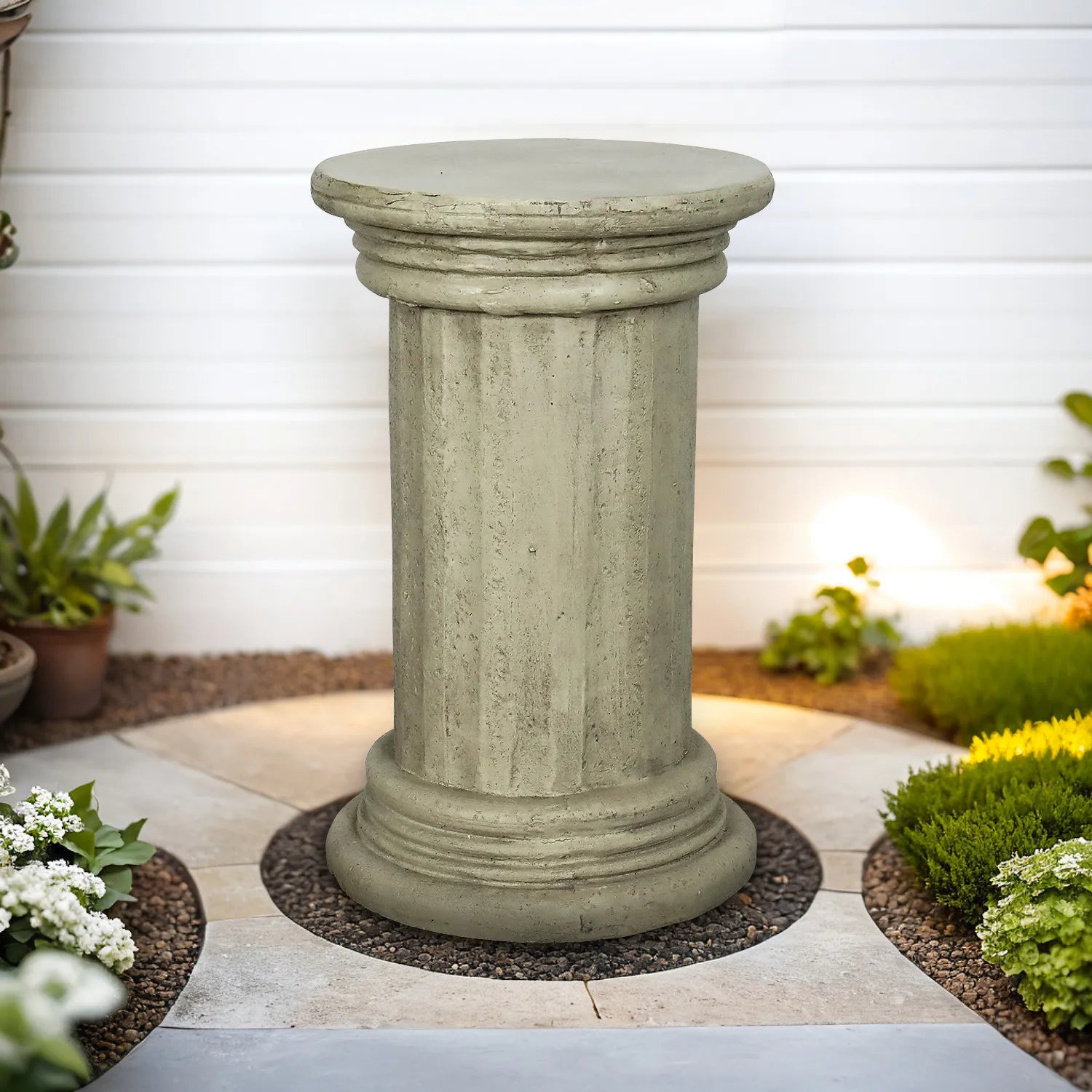 Timeless column-inspired concrete side table placed on a patio against a clean white wall.
