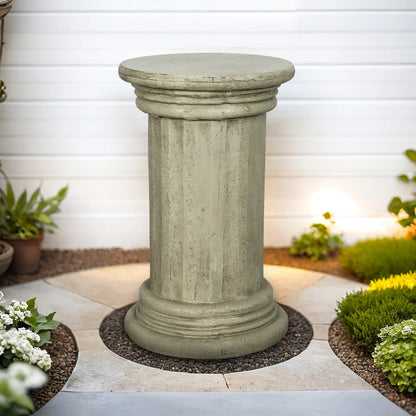Timeless column-inspired concrete side table placed on a patio against a clean white wall.
