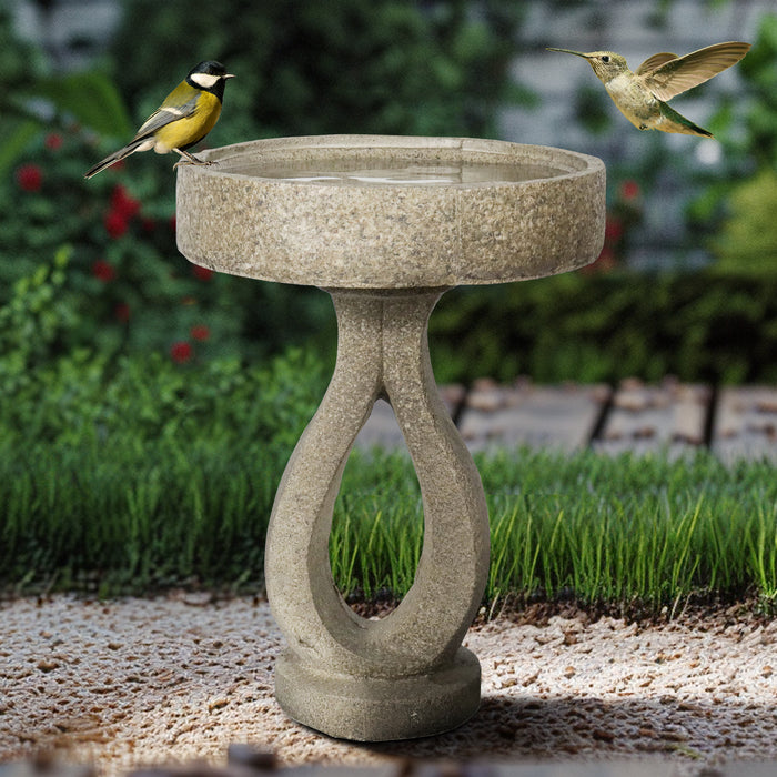 Vibrant birds flocking to the contemporary minimalist concrete garden bird bath on a gravel pathway.