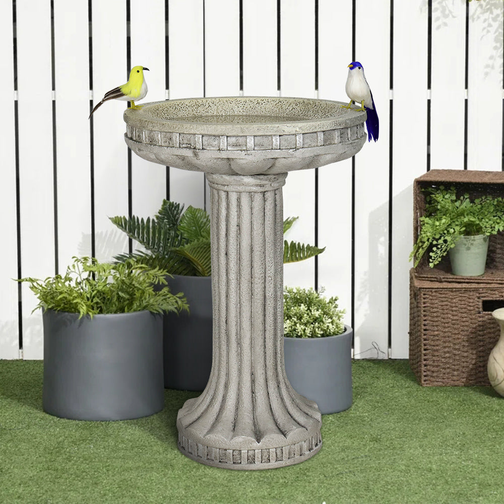 Vintage stone-like concrete birdbath in a cozy backyard