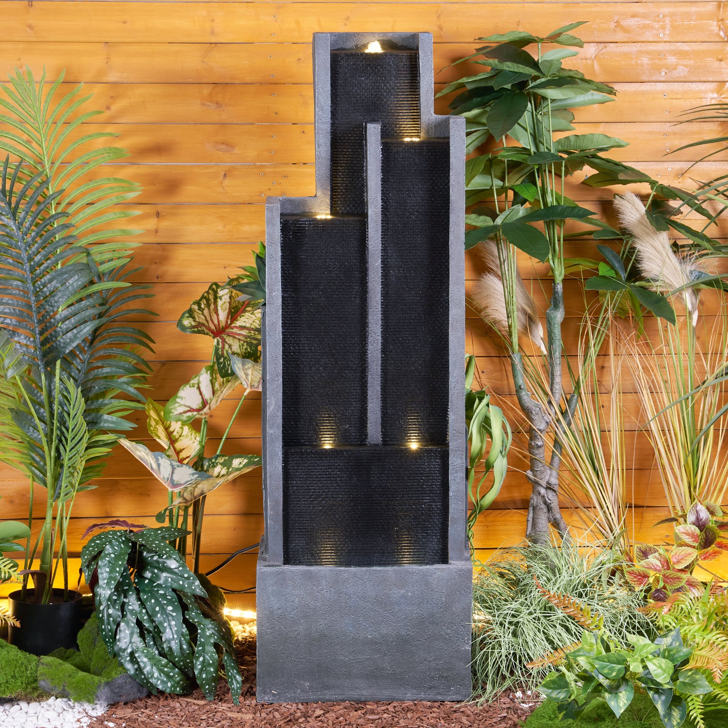 Weatherproof natural stone look cascading fountain decorating a modern outdoor patio space.