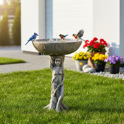 Wild birds perched on the classical goddess statue bird bath located on a green lawn near a modern patio.