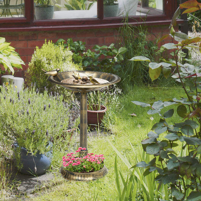 antique bronze pedestal bird bath with flowers planted in ground-level base bowl beside a garden path